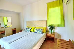 sypialnia z łóżkiem z niebieskimi i żółtymi poduszkami w obiekcie Erodios Hotel w mieście Karistos