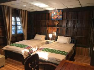 two beds in a room with wooden walls at Songthai Suvarnabhumi in Ban Khlong Si