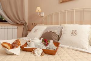 Una cama con una bandeja de comida y cruasanes. en B&B IL CASALETTO, en Monte Porzio Catone
