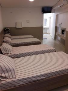 three beds are lined up in a room at Hotel YES (Adult Only) in São Paulo