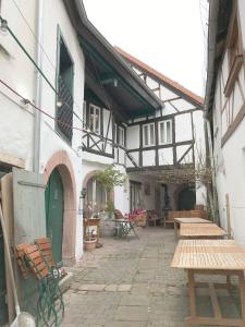 un patio extérieur avec des bancs en bois et un bâtiment dans l'établissement Fuxbau, à Neustadt an der Weinstraße