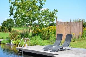 two chairs sitting on a dock next to a body of water at B&B Pipowagen "de Luxe" op Wellness Camping en B&B in Winterswijk-Meddo