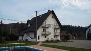 a white house with a black roof and a pool at Noclegi pod Brzegiem in Zawoja