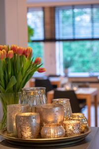 ein Tablett mit Vasen und Blumen auf dem Tisch in der Unterkunft Hotel Auberge St. Pol in Knokke-Heist