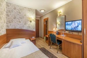 a bedroom with a bed and a desk with a television at Hotel Doris in Oborniki