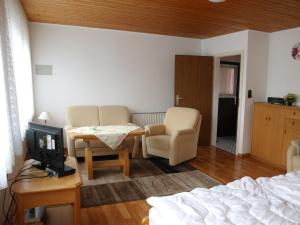 a bedroom with a bed and a tv and chairs at Haus Hopp - Bungalow in Dahme