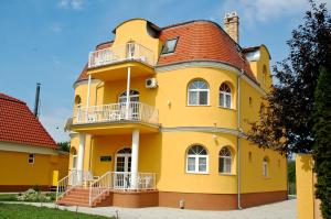 a yellow house with a red roof at Kastely Panzio II. in Hajdúszoboszló