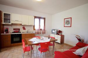 a kitchen and dining room with a table and red chairs at Residence Ai Campi Da Golf Saturnia in Saturnia