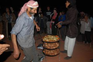 a man standing next to a table with a cake at Bedouins life camp in Aqaba