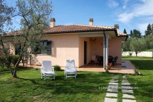 dos sillas blancas sentadas en el patio de una casa en Residence Ai Campi Da Golf Saturnia en Saturnia