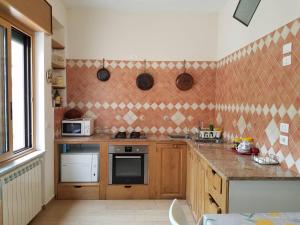 kuchnia z drewnianymi szafkami i ścianą wyłożoną kafelkami w obiekcie Casa di Chiara w mieście Vietri sul Mare
