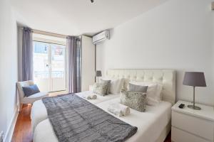 um quarto branco com uma cama grande e uma janela em Casa Portuguesa Chiado 25 em Lisboa