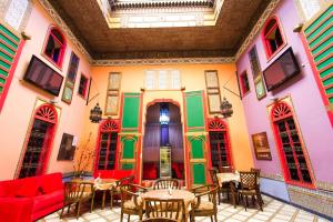 Riad Haj Palace & Spa في فاس: غرفة بها جدران ملونة وطاولات وكراسي