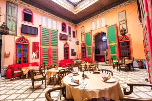 um restaurante com mesas e cadeiras e persianas vermelhas e verdes em Riad Haj Palace & Spa em Fez