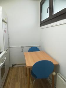 Il comprend une petite cuisine avec une table en bois et deux chaises bleues. dans l'établissement Hannover Messe-Wohnung, à Hanovre