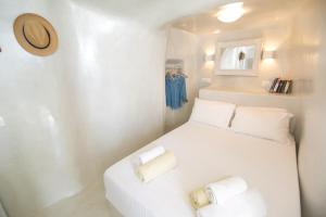 a small room with a white bed with two pillows at White Cave House in Oia