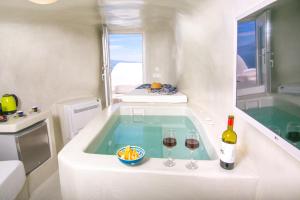a bath tub with two glasses of wine and a bottle at White Cave House in Oia