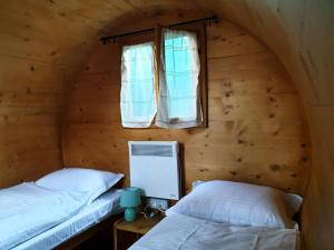 two beds in a wooden room with a window at Zozo House in Braşov