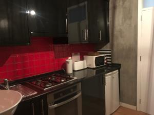 una cocina con armarios negros y una pared de azulejos rojos en Baixa, en Lisboa