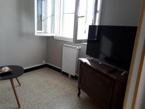 una sala de estar con TV de pantalla plana en una cómoda en A l'Ombre du Figuier, en Meynes
