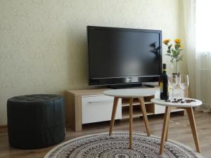 een woonkamer met een televisie en een tafel met een kruk bij Kaštonų apartamentai in Klaipėda
