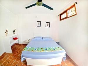 Hostal Dumbira في تاجانجا: غرفة نوم بسرير ومروحة سقف