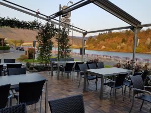 a patio with tables and chairs with a view of a river at Hotel "Zum Moseltal" in Mehring