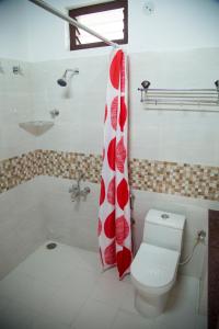 a bathroom with a red and white shower curtain and a toilet at Sunset Valley Homestay in Chikmagalūr