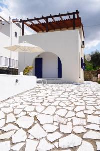 un patio de piedra frente a un edificio blanco con sombrilla en Villa Elan, en Mouríon