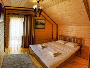 a bedroom with a large bed in a wooden room at Коло Гір in Kolochava