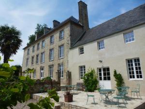 a building with tables and chairs in front of it at Manoir De Savigny in Valognes