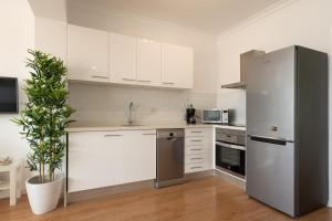 La cuisine est équipée de placards blancs et d'un réfrigérateur en acier inoxydable. dans l'établissement Living Las Canteras Homes - BEACH HOME, à Las Palmas de Gran Canaria