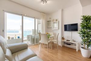 - un salon avec un canapé et une table avec des chaises dans l'établissement Living Las Canteras Homes - BEACH HOME, à Las Palmas de Gran Canaria