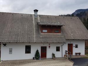 a white building with a roof with a tree in front at Vaznik Farm House Apartments in Bled