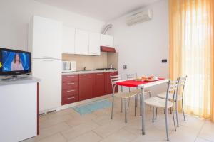 una cucina con tavolo e sedie rossi e una TV di Villa Maria a Caorle
