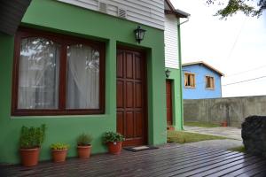 a green house with a wooden door and potted plants at Selknam in Ushuaia