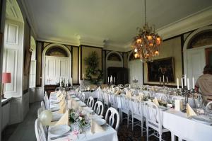 a room with white tables and white chairs and a chandelier at Husby Säteri in Söderköping