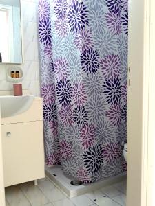 baño con cortina de ducha de color púrpura y blanco en Sitia Holidays 1 en Sitia