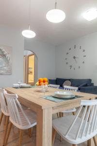 a dining room table with white chairs and a clock at John Apartments in Dhrepanon