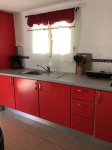 a kitchen with red cabinets and a sink and a window at La tourterelle de Neron in Le Moule