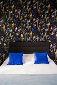 a bed with blue pillows in front of a wall at Le Jardin, chambres d'hôtes en Baie de Somme in Cahon