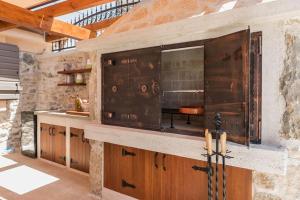 een keuken met houten kasten en een stenen muur bij Villa Hirundo Rustica in Skradin