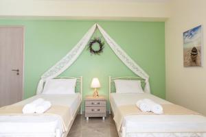 2 camas en una habitación con paredes verdes en John Apartments, en Dhrepanon