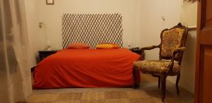 a bedroom with a bed with an orange blanket and a chair at Les Marronniers in Reillanne