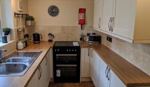 cocina con armarios blancos, fregadero y fogones en Pavilion House en Exeter