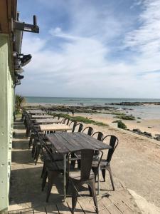 a row of wooden tables and chairs on the beach at Entre Terre et Mer in Réville
