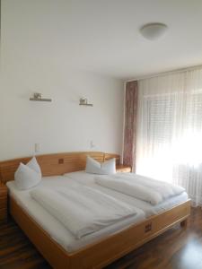 um quarto com uma cama grande com lençóis brancos e uma janela em Hotel Garni am Hechenberg em Mainz