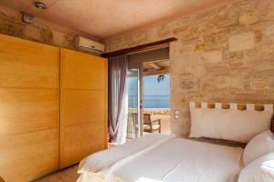 a bedroom with a bed and a view of the ocean at Elegant 2-Villa Stone Estate with Pool & Sea Views in Agia Pelagia +57 photos