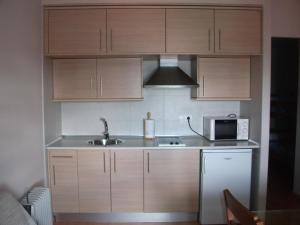 cocina con armarios de madera, fregadero y microondas en Apartamentos Sierra Nevada Welcome, en Sierra Nevada