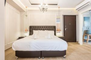una camera da letto con un grande letto bianco e un lampadario a braccio di Syntagma Luxury Living One “LL1” Apartments ad Atene